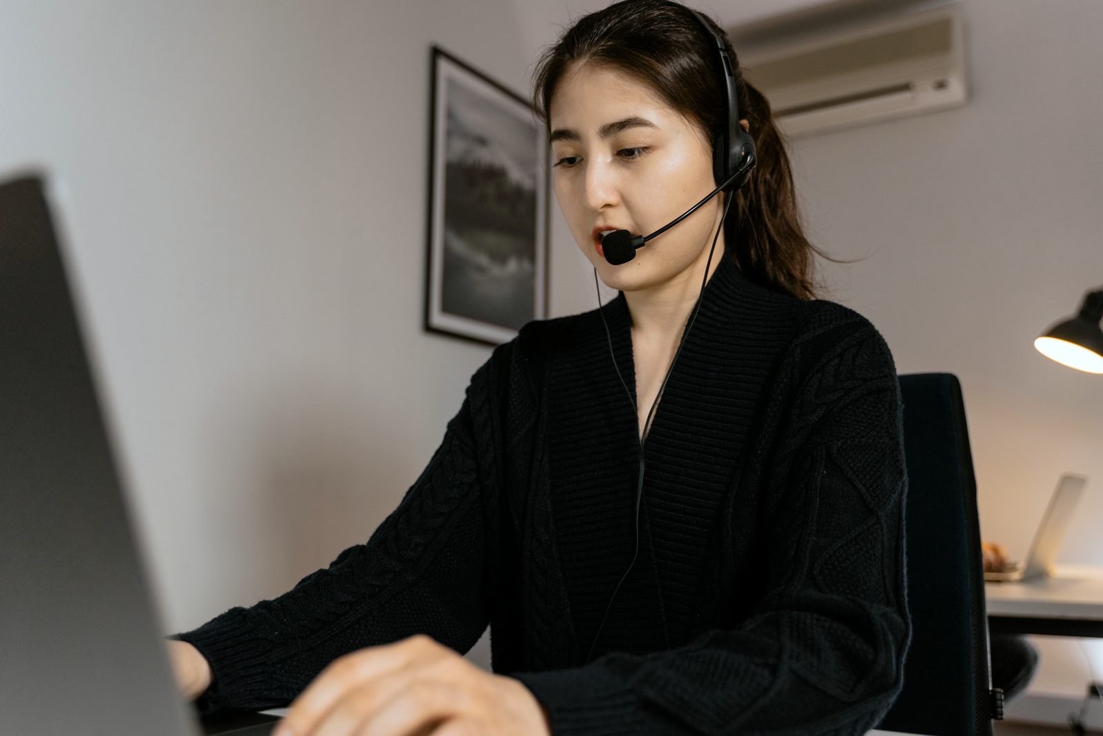 A customer care agent with a headset talks with a customer in front of the computer
