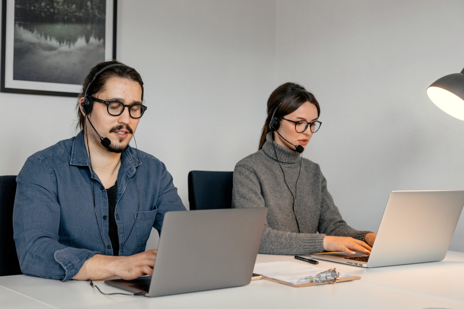 Due operatori con la cuffia al lavoro al portatile