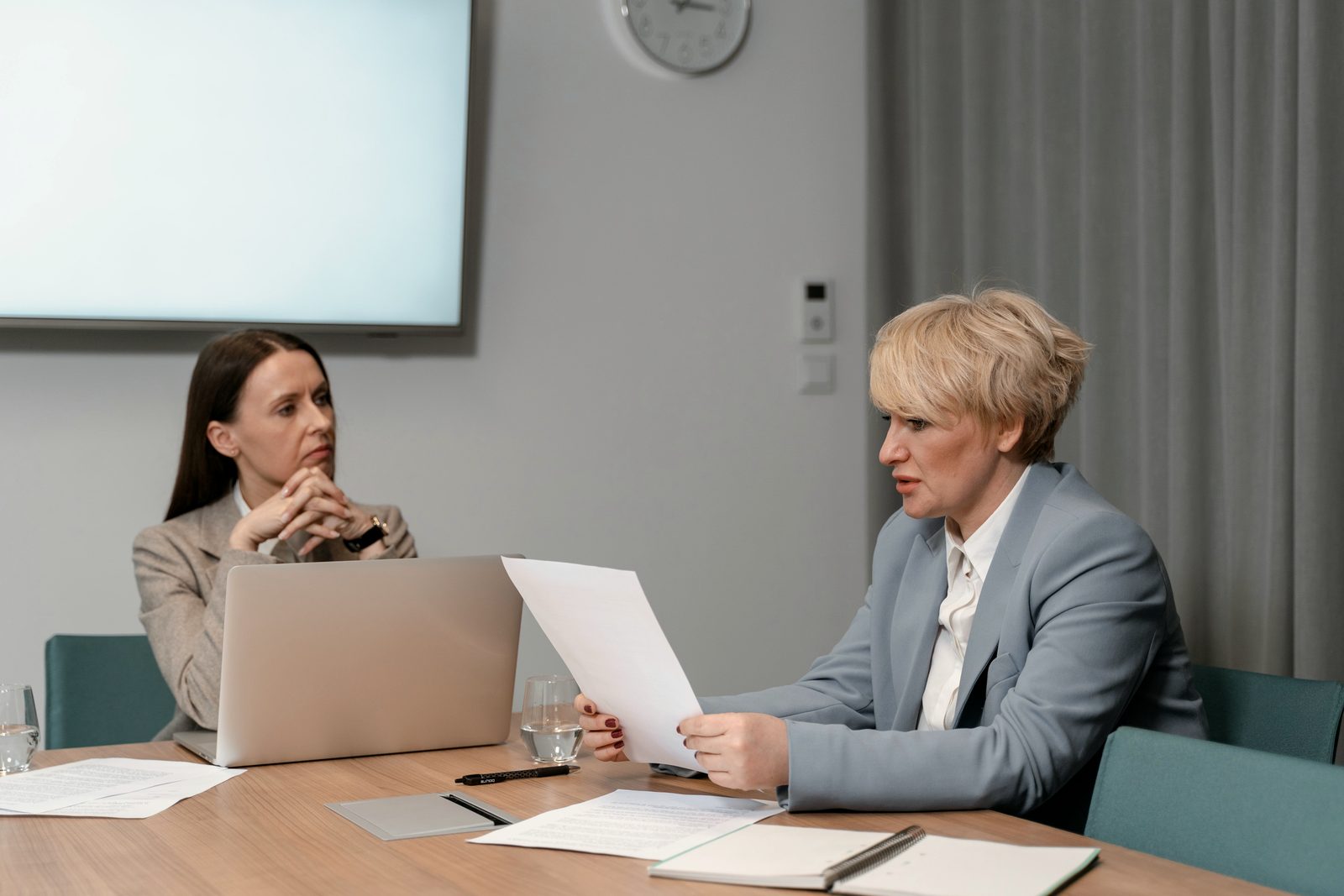 A manager talks with a colleague in a one-to-one meeting, at a meeting-room table