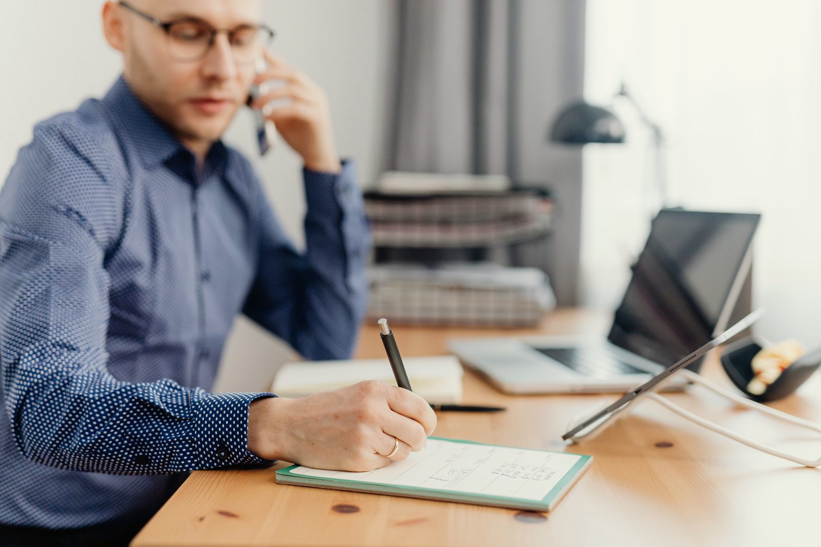 A professional on the phone takes notes at the desk