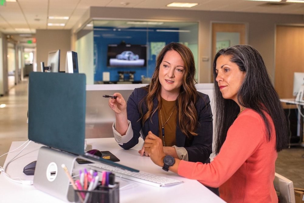 Two professionals review a document together on a screen